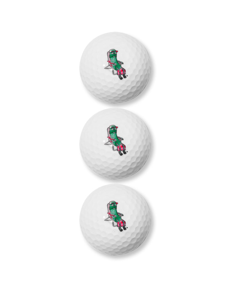 three golf balls with pickle in lounge chair on them
