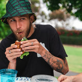 man eating sandwich with "grillo's pickles" bucket hat
