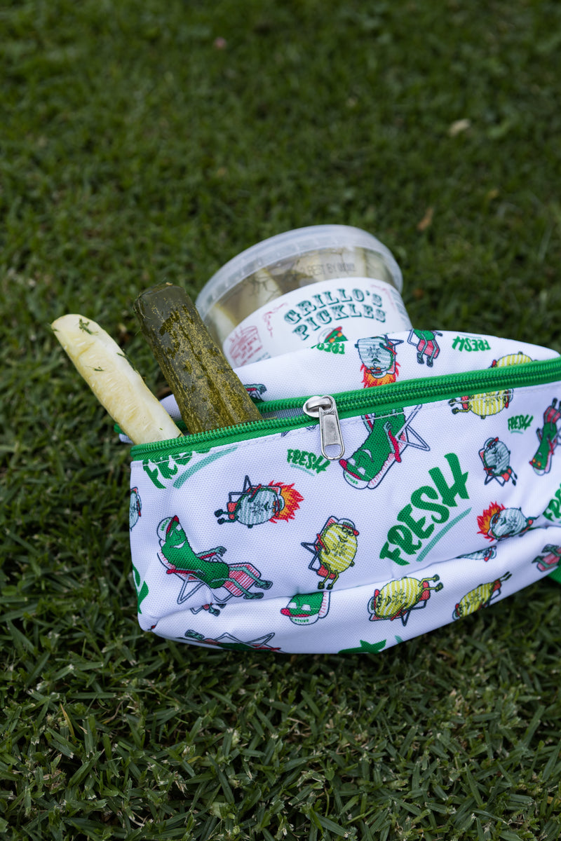 white and green fanny pack on grass with pickles coming out of it