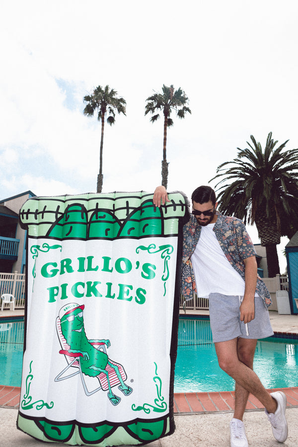 man leaning on pool floaty in shape of grillo's pickle jar